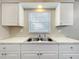 Bright kitchen featuring white cabinets, marble countertops, and a stainless steel sink at 130 Aragon Ave, Umatilla, FL 32784