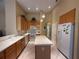 Light and bright kitchen featuring an island, white appliances, and maple-colored cabinetry at 13250 Meergate Cir, Orlando, FL 32837
