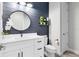 Modern bathroom featuring a shiplap accent wall, round mirror, white vanity and decorative shelving with greenery at 13807 Tybee Beach Ln, Orlando, FL 32827