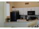 Clean kitchen features white cabinetry, bar seating and black appliances at 15910 Mercott Ct, Clermont, FL 34714