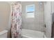 Bright bathroom features shower and tub combination with neutral tile surround and floral shower curtain at 1703 Daystar Dr, Haines City, FL 33844