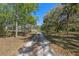 Long gravel driveway leading to a charming home surrounded by mature trees on a sunny day at 20 Lido Rd, Winter Springs, FL 32708