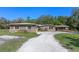 Exterior elevation featuring stone accents, a metal roof, mature trees, and lush green lawn at 20 Lido Rd, Winter Springs, FL 32708