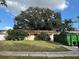 Front of the home with a large tree and a dumpster in the driveway at 2115 Messina Ave, Orlando, FL 32811