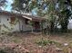 Abandoned home exterior with covered porch, boarded windows, and untamed vegetation, needing restoration at 2115 Messina Ave, Orlando, FL 32811