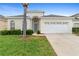 Charming single-story home with a well-manicured lawn and a two-car garage on a sunny day at 2263 Wyndham Palms Way, Kissimmee, FL 34747