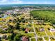 An aerial view showcases a home nestled in a community surrounded by lush greenery and a serene lake at 2726 La Alameda Ave, Kissimmee, FL 34746