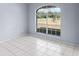 This vacant bedroom features a large sunny window and neutral tiled flooring at 2726 La Alameda Ave, Kissimmee, FL 34746