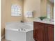 Inviting bathroom featuring a corner bathtub with jets, vanity with a dark wood finish, and a charming arched window at 5062 Otters Den Trl, Sanford, FL 32771