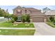 Two-story home with well-manicured lawn, shrubs, and brown two car garage at 613 Crownclover Ave, Orlando, FL 32828