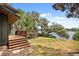 An exterior view of a home's backyard and deck, with steps leading down to the lawn near a body of water at 613 Lake Ave, Altamonte Springs, FL 32701