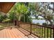 A wood deck with a railing overlooking water, surrounded by mature trees and lush greenery at 613 Lake Ave, Altamonte Springs, FL 32701