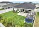 Inviting backyard features a covered patio with dining and lounge furniture, a green lawn, and a play area at 62 Polermo Ave, St Cloud, FL 34771