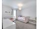 Cozy bedroom with a white crib, pink daybed, and soft gray carpet at 62 Polermo Ave, St Cloud, FL 34771
