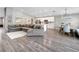 Open-concept living space with modern gray wood floors, a large gray sectional, and bright white kitchen at 62 Polermo Ave, St Cloud, FL 34771