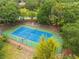 Aerial view of tennis court, surrounded by trees and lush landscaping, enhancing the community's recreational amenities at 709 Strihal Loop, Oakland, FL 34787