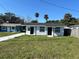Charming white home with dark doors, a covered patio, and a freshly painted driveway at 73 Brooks Dr, Ormond Beach, FL 32176