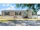 Charming single-story home with a front porch, neutral siding, and black shutters against a backdrop of blue skies at 8218 Pine Island Rd, Clermont, FL 34711