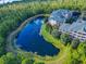 Scenic aerial of condo buildings surrounded by a tranquil pond and lush trees, showcasing a serene residential community at 9061 Treasure Trove Ln # 403, Kissimmee, FL 34747