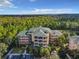 Wide aerial shot of the condo building surrounded by lush greenery and trees, with a parking area visible at 9061 Treasure Trove Ln # 403, Kissimmee, FL 34747