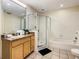 Well-lit bathroom features a glass enclosed shower, a tub, and a granite topped vanity with a large mirror at 9061 Treasure Trove Ln # 403, Kissimmee, FL 34747
