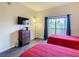Cozy bedroom featuring twin beds, dark wood floors, and a mounted TV at 9061 Treasure Trove Ln # 403, Kissimmee, FL 34747