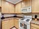 Bright kitchen with light wood cabinetry, white appliances, and tiled floors at 9061 Treasure Trove Ln # 403, Kissimmee, FL 34747
