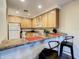 A bright kitchen featuring natural wood cabinets and a breakfast bar area with chairs at 9061 Treasure Trove Ln # 403, Kissimmee, FL 34747