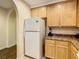 View of kitchen features white refrigerator and light wood cabinets; view to entry hallway at 9061 Treasure Trove Ln # 403, Kissimmee, FL 34747