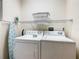 Convenient laundry room with white washer and dryer, wire shelf, ironing board and light blue accents at 9061 Treasure Trove Ln # 403, Kissimmee, FL 34747