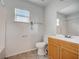 Well-lit bathroom features a window, vanity, toilet, and a combination of tile and laminate flooring at 927 Cambridge Ct, Kissimmee, FL 34758