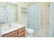 Well-lit bathroom featuring a shower-tub combo with a blue-striped curtain and wooden vanity at 9635 Fenrose Ter, Orlando, FL 32827