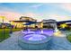 Inviting backyard with a uniquely shaped pool, connected hot tub, fountain feature and ample seating under the sunset at 9877 Laurel Berry Dr, Orlando, FL 32827