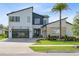 Contemporary two-story home featuring a glass garage door, modern design, and lush landscaping at 9877 Laurel Berry Dr, Orlando, FL 32827