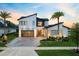 Modern two-story home featuring a glass garage door, lush landscaping and an eye-catching elevated roofline at 9877 Laurel Berry Dr, Orlando, FL 32827