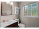 This bathroom features a vanity, a decorative mirror with lighting, a toilet, and a bright window at 101 E Lauren Ct, Fern Park, FL 32730