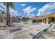 Community pool with sun loungers, palm trees, and covered seating areas on a bright, sunny day at 1041 Park Ridge Cir, Kissimmee, FL 34746