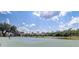 Scenic tennis court view with lush greenery, surrounding houses, and a clear blue sky with fluffy clouds at 1041 Park Ridge Cir, Kissimmee, FL 34746