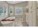 Bright bathroom with marble floors, a soaking tub, white cabinets, a double vanity and natural light at 11335 Winston Willow Ct, Windermere, FL 34786