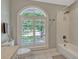 Bright bathroom featuring a shower-tub combination and an arched window with white shutters at 11335 Winston Willow Ct, Windermere, FL 34786