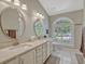 Updated bathroom with dual sinks, a quartz countertop, and a large window with plantation shutters at 11335 Winston Willow Ct, Windermere, FL 34786