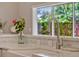 Close-up of a kitchen sink featuring white countertops, a modern faucet, a flower vase and decorative tile backsplash at 11335 Winston Willow Ct, Windermere, FL 34786