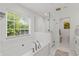 Bright bathroom with a soaking tub, glass-enclosed shower, and a large window with a lush view at 1207 W New Hampshire St, Orlando, FL 32804