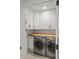 Functional laundry room includes modern washer, dryer, wood countertop, and white cabinets at 1207 W New Hampshire St, Orlando, FL 32804