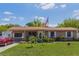Charming single-story home featuring a lush lawn, lovely garden beds, and an American flag at 1219 Blue Spring Ct, Ocoee, FL 34761