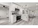 Open kitchen with stainless steel appliances, white cabinetry and a view into the living area at 13 Fanfair Ave, Orlando, FL 32811