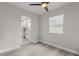 Bright living room featuring gray wood-look flooring and modern ceiling fan, leading to the adjacent white kitchen at 13 Fanfair Ave, Orlando, FL 32811