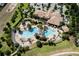 Aerial view of the community pool showcasing ample lounge chairs, palm trees, and a building with a tile roof at 1300 Island Green St, Davenport, FL 33896