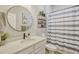 Modern bathroom featuring quartz countertop, a round mirror, decorative plants, and patterned shower curtain at 13299 Serene Valley Dr, Clermont, FL 34711