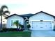 Charming home featuring a two-car garage, well-manicured lawn, and inviting entryway with decorative features at 13299 Serene Valley Dr, Clermont, FL 34711
